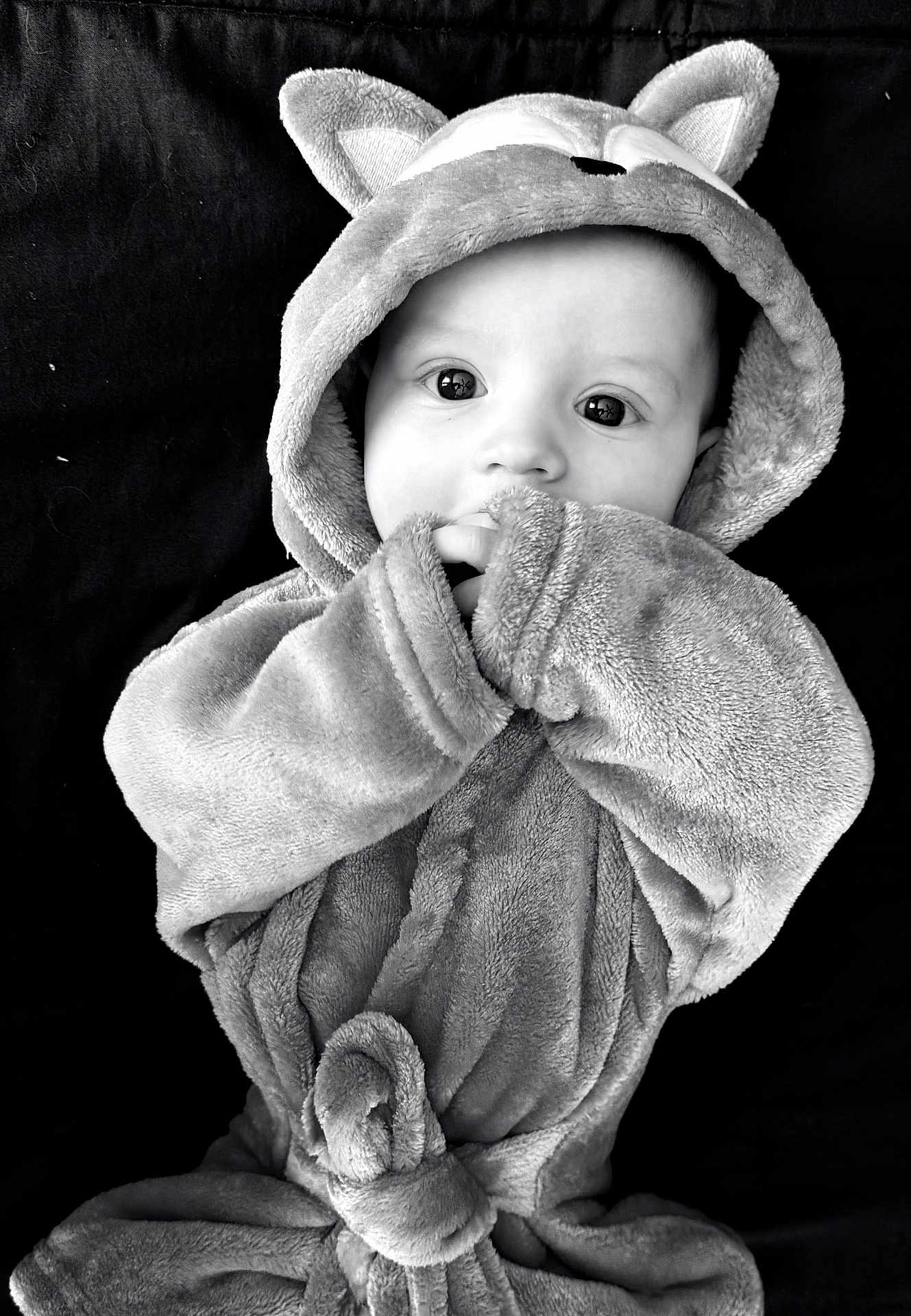 Cain is registered to the contest to win money with this photo: baby, child, hood, robe, ears, cute, cozy, soft_texture, black_and_white, portrait, face, wide_eyes, hand, fingers, infant, clothing, background, indoor, expression, close_up
