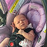 Everleigh is registered to the contest to win money with this photo: baby, infant, child, car_seat, carriage, harness, safety_straps, purple, floral_pattern, sitting, lying_down, serious_expression, hand_gesture, portrait, close_up, vehicle_interior, baby_clothing, pink, warning_label, photography