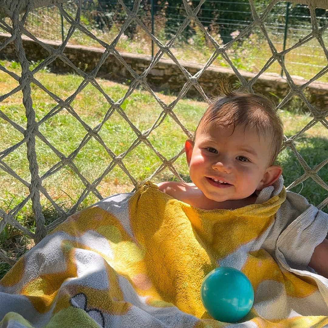 Taël a rejoint le concours — aidez-le/la à gagner de superbes lots ! baby, ball, bright, child, face, garden, grass, hammock, happy, nature, outdoor, person, playful, relaxing, shade, smile, summer, sunlight, towel, tree