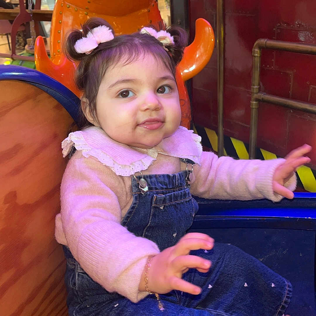 Kiana a rejoint le concours — aidez-le/la à gagner de superbes lots ! amusement_ride, baby, bow_hair, bracelet, child, colorful, cute, denim_overalls, face, hair_buns, indoor, mall_interior, pink_sweater, playful, portrait, sitting, smile, sneakers, toddler, wooden_seat