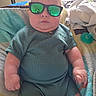 Isaac joined the competition — help win amazing prizes! baby, infant, sunglasses, green_clothing, blanket, indoor, cute, chubby, portrait, child, relaxed, serious_expression, short_hair, hand, furniture, pacifier, casual, soft_lighting, comfort, home