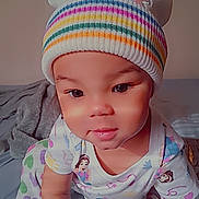 Malanii is registered to the contest to win money with this photo: toddler, child, baby, beanie, hat, pajamas, colorful, striped, heart_pattern, indoors, bed, blanket, crawling, cute, smiling, face, pom_pom, cartoon_character, emojis, person