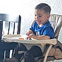 toddler, child, high_chair, toy, toy_truck, blue_shirt, smiling, happy, indoor, wooden_chair, playtime, young_child, short_hair, person, furniture, seat, table, wall, casual_clothing, daylight