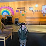 Sao participe au concours pour gagner de l'argent avec cette photo : child, indoor, coat, beanie, backpack, rainbow, wall, chair, stroller, floor, bench, clock, sign, person, young_child, nursery, daycare, cute, curious, playroom