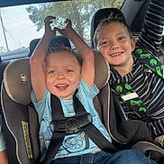 Kyson is registered to the contest to win money with this photo: child, kids, car_seat, car_interior, seatbelt, smiling, happy, boy, blue_shirt, striped_shirt, jeans, window, sunlight, hair, seat, playful, safety, transportation, casual_clothing, portrait