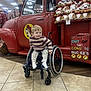 beaver_logo, cartoon_logo, casual_wear, child, clothing, happy, holiday_merchandise, indoor, light_reflection, person, plush_toys, red_truck, retail, smiling, store_interior, tiled_floor, toy_display, wheelchair, wheelchair_user, young_child