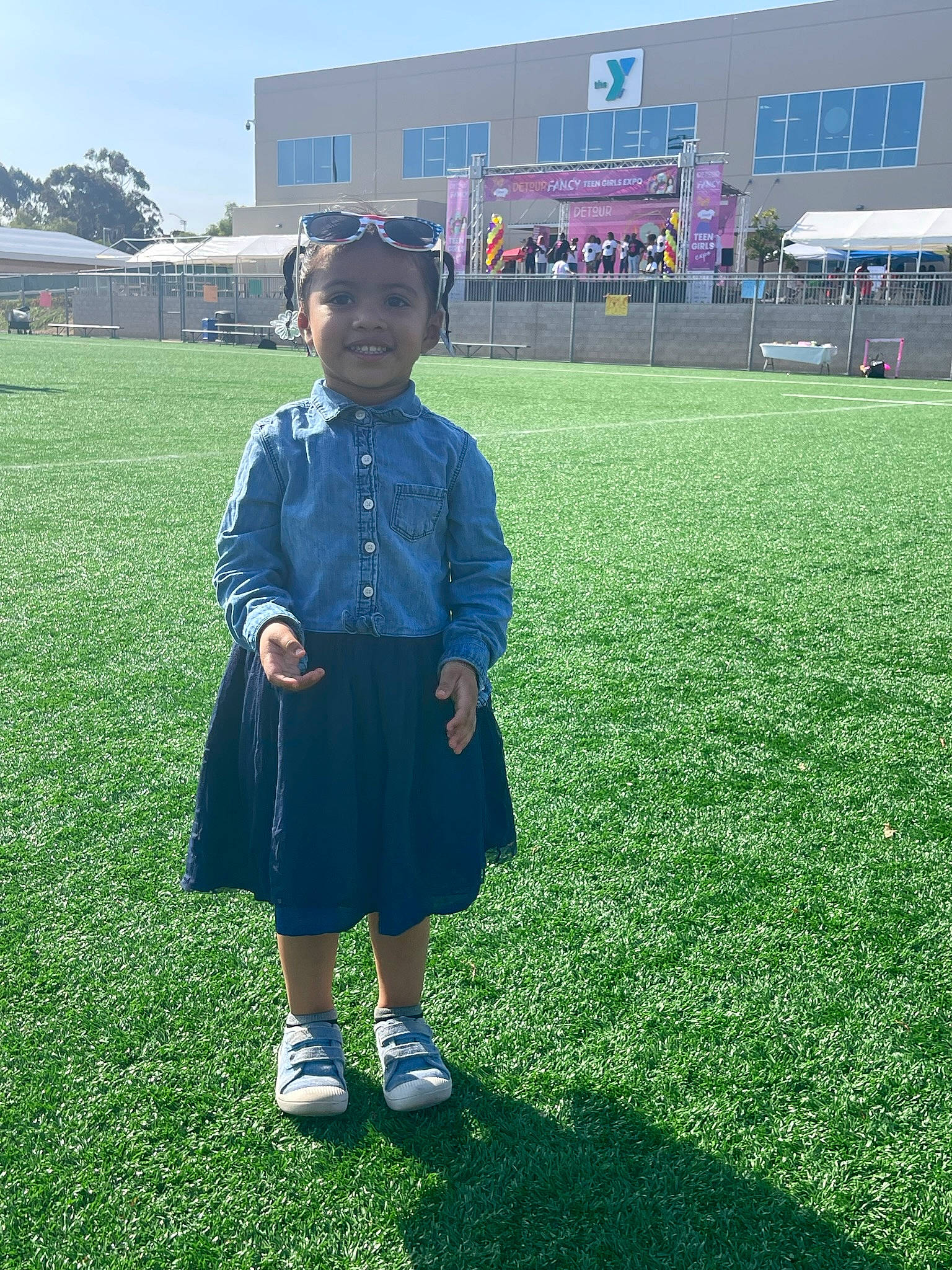 Haley is registered to the contest to win money with this photo: artificial_turf, building, electric_blue, event, flooring, fun, grass, grassland, hat, headwear, joy, leisure, people_in_nature, person, player, sky, sleeve, smile, t_shirt, team