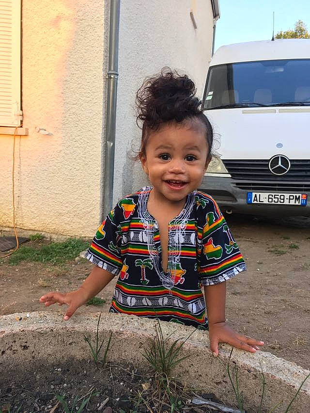 Lola Pita a rejoint le concours — aidez-le/la à gagner de superbes lots ! asphalt, automotive_exterior, automotive_lighting, automotive_tire, baby_toddler_clothing, bumper, car, eye, face, grass, grille, hood, joy, motor_vehicle, person, road_surface, smile, t_shirt, tire, toddler