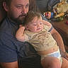 man, child, toddler, beard, diaper, shirt, couch, toy, indoor, relaxed, family, casual, seated, portrait, home, comfort, playful, parent, care, bonding