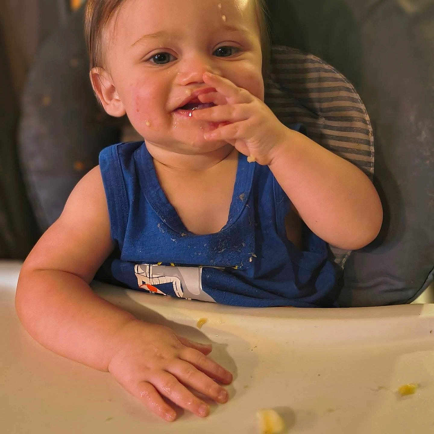 Castiel is registered to the contest to win money with this photo: toddler, child, messy, high_chair, blue_shirt, food, snack, face, hand, table, indoor, curious, mess, cute, person, baby, seat, expression, skin, hair