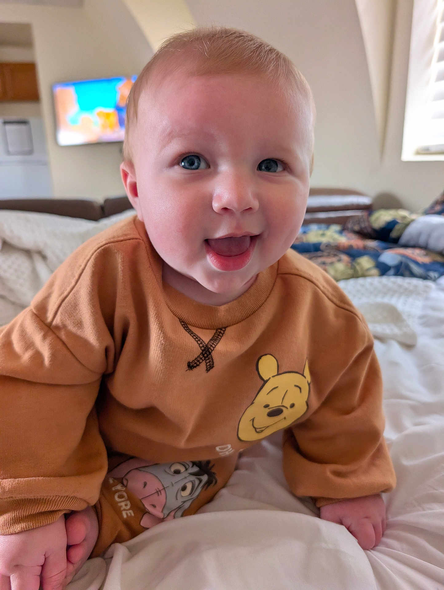 Kellen joined the competition — help win amazing prizes! baby, child, smiling, blue_eyes, sweatshirt, winnie_the_pooh, eeyore, bed, blanket, indoor, crawling, cute, happy, person, face, infant, clothing, room, furniture, portrait