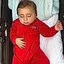 baby, sleeping, red_onesie, stroller, blanket, infant, child, cozy, peaceful, cute, portrait, resting, indoors, soft, clothing, closeup, baby_sleepwear, newborn, human, relaxation