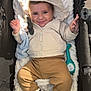 baby, child, smiling, hoodie, plush_toy, stroller, blanket, yellow_socks, cozy, cute, infant, clothing, portrait, happy, indoor, baby_toy, warm, face, sitting, casual