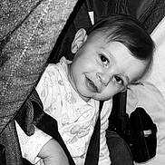 Myliana participe au concours pour gagner de l'argent avec cette photo : baby, child, smiling, stroller, seatbelt, black_and_white, portrait, infant, clothing, fabric, hand, face, cute, indoor, person, seat, head, young, comfort, closeup