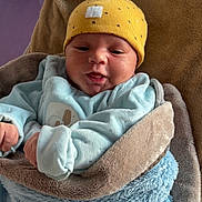 Hautaki participe au concours pour gagner de l'argent avec cette photo : baby, infant, blanket, hat, yellow_hat, blue_blanket, clothing, face, portrait, newborn, cute, warm, soft_texture, indoors, person, wrapped, smiling, child, cozy, sleepwear