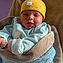 baby, infant, blanket, hat, yellow_hat, blue_blanket, clothing, face, portrait, newborn, cute, warm, soft_texture, indoors, person, wrapped, smiling, child, cozy, sleepwear
