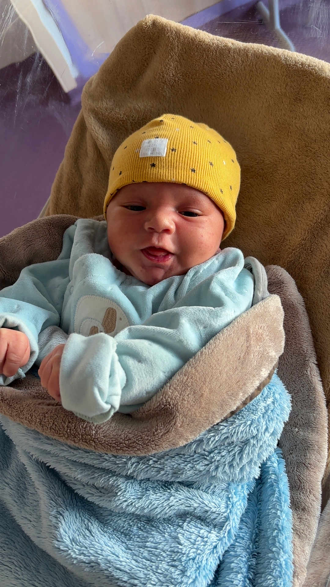 Hautaki participe au concours pour gagner de l'argent avec cette photo : baby, infant, blanket, hat, yellow_hat, blue_blanket, clothing, face, portrait, newborn, cute, warm, soft_texture, indoors, person, wrapped, smiling, child, cozy, sleepwear