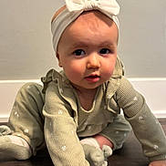 Polina is registered to the contest to win money with this photo: baby, child, headband, bow, crawling, floor, wooden_floor, green_outfit, long_sleeves, socks, indoor, curious, hand, face, person, infant, cute, young_child, portrait, exploring
