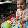 baby, child, toy, activity_center, smiling, indoor, couch, blanket, floor, baby_gear, happy, person, infant, play, colorful, furniture, clothing, head, hands, living_room