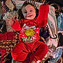 baby, child, pajamas, red_clothing, grinch, smiling, blanket, patchwork, toy, floor, wipes, playful, happy, indoor, person, infant, cute, face, hands, feet