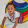 baby, backpack, child, clothing, crawling, curious, earrings, face, floor, giraffe, indoor, playroom, portrait, rainbow, shirt, smiling, tiles, toddler, toy, tunnel