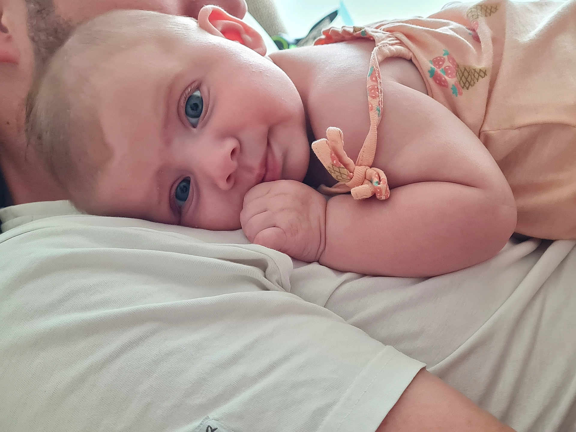 Victoria a rejoint le concours — aidez-le/la à gagner de superbes lots ! baby, child, infant, person, face, blue_eyes, skin, arm, hand, clothing, fabric, snuggling, comfort, closeup, portrait, cute, soft, resting, peach_outfit, pineapple_pattern