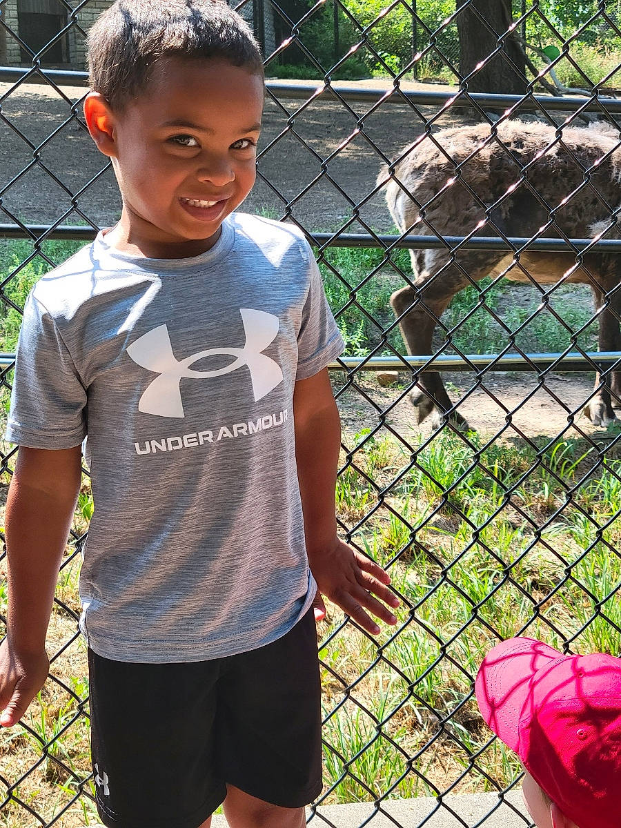 Lance is registered to the contest to win money with this photo: chain_link_fencing, fence, grass, green, happy, joy, leisure, mammal, mesh, nature, net, person, plant, player, recreation, shorts, sleeve, smile, t_shirt, tree