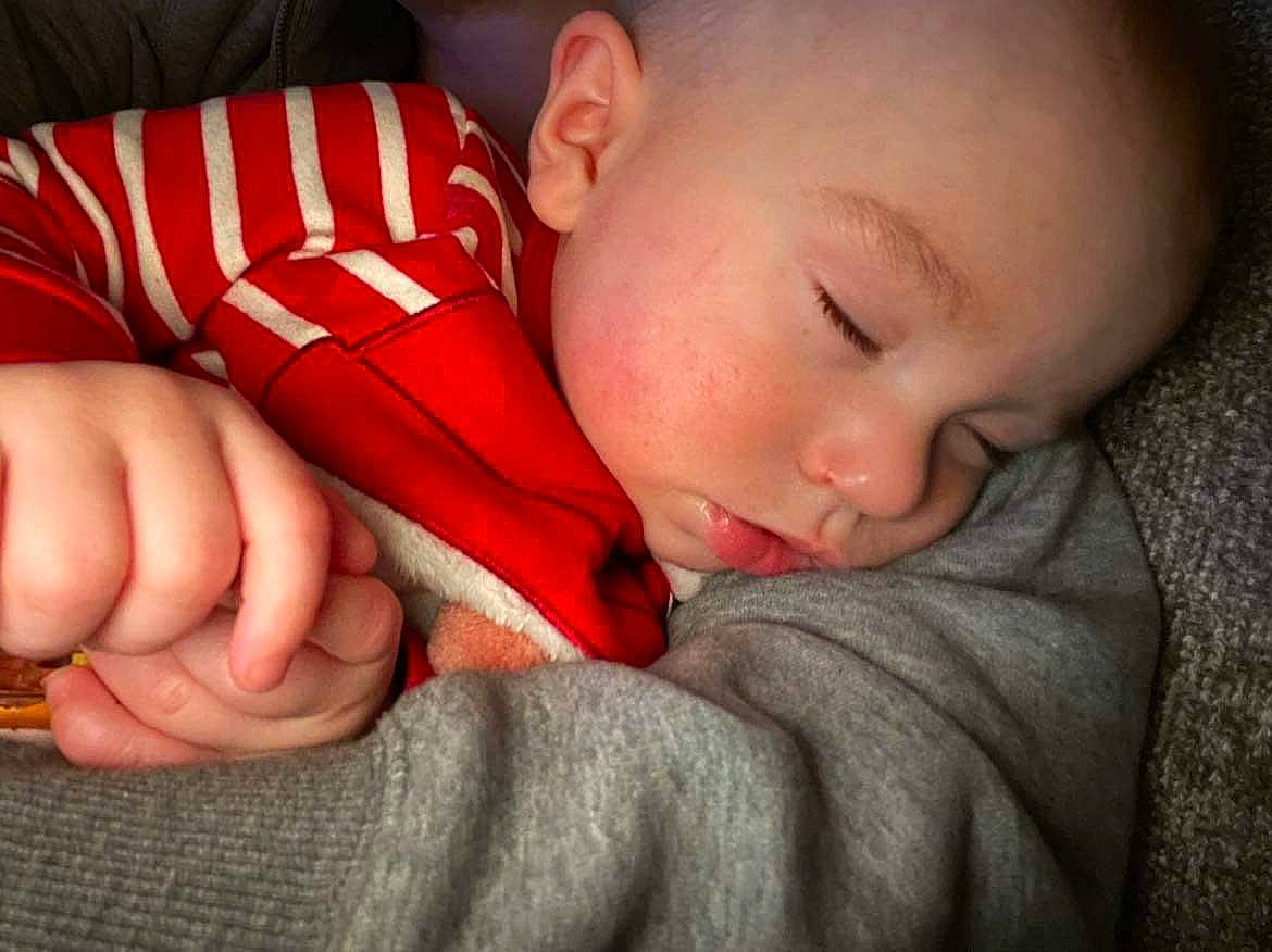 Bret is registered to the contest to win money with this photo: baby, baby_sleeping, baby_toddler_clothing, cheek, comfort, finger, foot, gesture, human_leg, linens, lip, mouth, nail, nose, pattern, person, sitting, skin, thumb, toddler