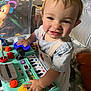 toddler, child, toy, play, keyboard, colorful, buttons, smile, indoor, cushion, clothing, person, face, hand, furniture, playpen, happy, young_child, activity, expression
