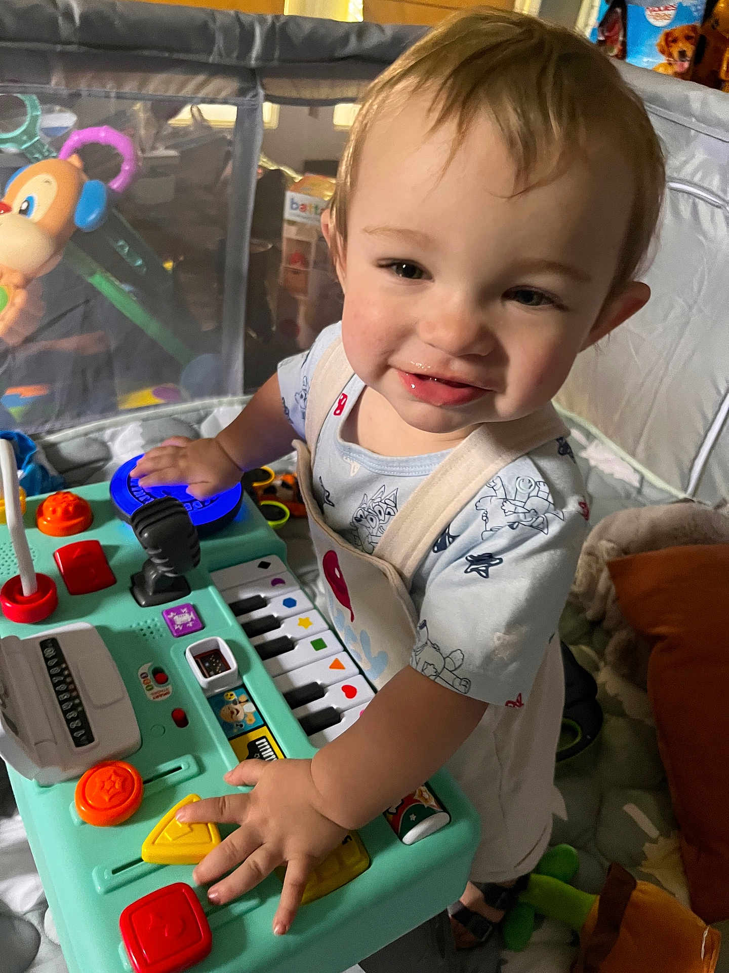 Bodhi is registered to the contest to win money with this photo: toddler, child, toy, play, keyboard, colorful, buttons, smile, indoor, cushion, clothing, person, face, hand, furniture, playpen, happy, young_child, activity, expression