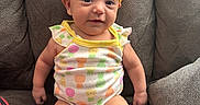 Alaynna is registered to the contest to win money with this photo: armchair, baby, child, colorful_clothing, couch, cute, front_view, furniture, headband, indoors, infant, onesie, orange_bow, photography, pineapple_pattern, portrait, sitting, smiling, textile, wide_eyed