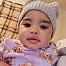 Kailani is registered to the contest to win money with this photo: baby, child, face, hat, knit_hat, bear_ears, cute, indoors, plaid_blanket, hand, teddy_bear_pattern, clothing, warm_lighting, portrait, cozy, infant, expression, looking_at_camera, close_up, soft_texture