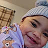 baby, smile, hat, knit_hat, pom_pom, teddy_bear, purple_clothing, child, face, cute, infant, happy, closeup, indoor, portrait, warm_clothing, soft_texture, adorable, person, baby_girl
