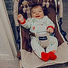 baby, child, smiling, pajamas, baby_rocker, toys, indoor, floor, wooden_floor, happy, person, infant, clothing, cute, seat, playtime, home, comfort, red_socks, text_overlay