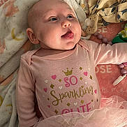 Summer is registered to the contest to win money with this photo: baby, infant, pink_clothing, tutu, blanket, pacifier, tongue_out, cute, playful, lying_down, soft_toys, patterned_pants, head, face, cheeks, sleeping_area, indoor, child, adorable, cozy