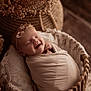 baby, closeup, cozy, cute, decor, dried_flower, flower, headband, indoors, infant, lace, newborn, peaceful, portrait, sleeping, smiling, soft_lighting, swaddled, wicker_basket, wrapped
