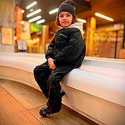 Elio participe au concours pour gagner de l'argent avec cette photo : beanie, bench, black_jacket, casual, child, cool_style, cozy, curious_eyes, curly_hair, fashion, footwear, indoor, modern, person, portrait, seated, urban, warm_lighting, wood_floor, young