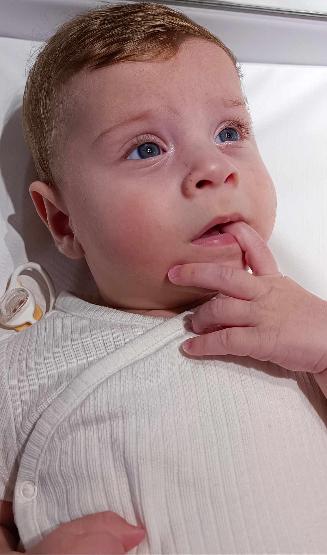 Eloan a rejoint le concours — aidez-le/la à gagner de superbes lots ! baby, infant, close_up, blue_eyes, hand, fingers, white_clothing, onesie, pacifier, face, skin, expression, portrait, child, cute, indoors, soft_light, young, curious, toddler
