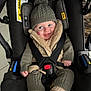 baby, car_seat, knit_hat, pom_pom, smiling, child, winter_clothing, safety_harness, cute, happy, indoor, warm_clothes, face, person, seat, straps, jacket, socks, cozy, infant