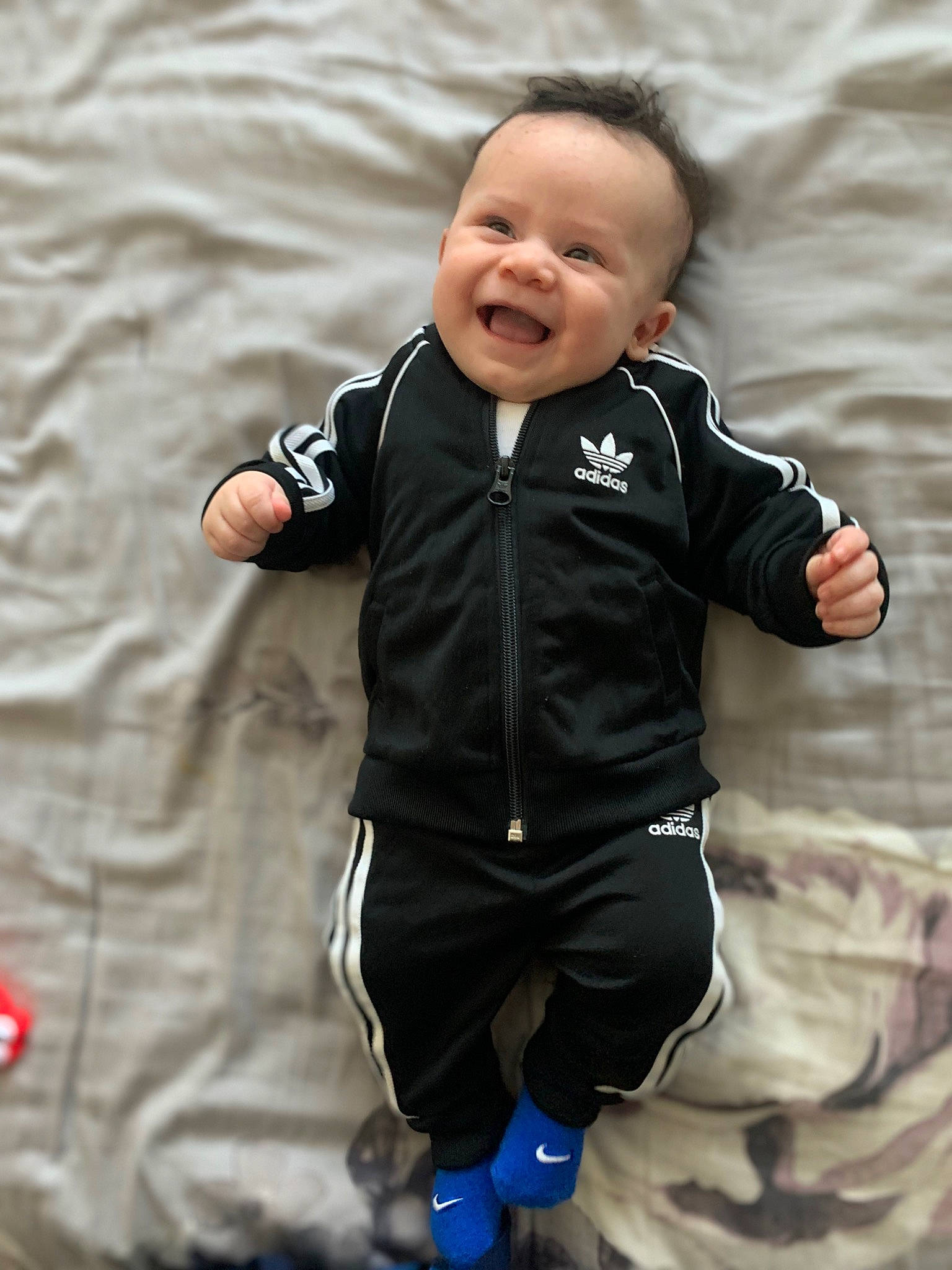 Leonel is registered to the contest to win money with this photo: baby, baby_toddler_clothing, cheek, child, comfort, fun, gesture, grey, happy, iris, mammal, outerwear, pattern, person, sitting, sleeve, smile, t_shirt, toddler, vertebrate