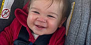Atlas is registered to the contest to win money with this photo: baby, child, car_seat, red_jacket, smiling, happy, infant, seatbelt, straps, hair, face, person, indoors, closeup, cute, safety, child_safety, car_interior, clothing, seat