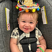 Atlas joined the competition — help win amazing prizes! baby, car_seat, smiling, sombrero, hat, infant, child, seatbelt, straps, warning_labels, clothing, hand, face, cute, sitting, indoor, colorful, cheerful, toy, closeup