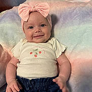 Ayla joined the competition — help win amazing prizes! baby, smiling, headband, pink_bow, infant, clothing, shorts, plush_blanket, pastel_colors, cute, happy, child, portrait, indoor, soft_texture, person, toddler, casual_wear, resting, closeup