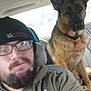 Bella is registered to the contest to win money with this photo: man, beard, glasses, beanie, hoodie, dog, german_shepherd, car_interior, seat, pet, animal, casual, portrait, selfie, indoor, companion, friendship, calm, looking_at_camera, winter_clothing