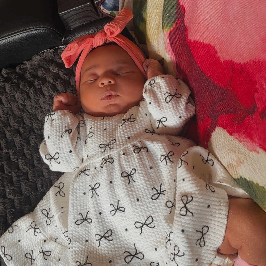 Imarah-Anne is registered to the contest to win money with this photo: baby, blanket, bow, child, couch, cozy, dress, floral, headband, indoors, infant, pattern, peaceful, pillow, pink, remote_control, resting, sleeping, sofa, white