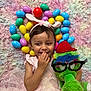 child, toddler, smiling, bunny_ears, pink_dress, stuffed_toy, glasses, red_hat, easter_eggs, colorful, fluffy_rug, playful, happy, indoors, cute, toy, celebration, portrait, hand_on_mouth, fun