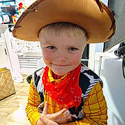 David is registered to the contest to win money with this photo: appliance, boy, cabinet, child, costume, cowboy_hat, door, face, hand, indoor, kitchen, light, person, playful, portrait, red_bandana, smile, wood_floor, yellow_shirt, young