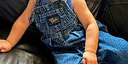 Koleson is registered to the contest to win money with this photo: baby, child, smiling, denim_overalls, blue_shirt, leather_couch, happy, sitting, indoor, cute, infant, portrait, person, skin, face, hand, foot, clothing, young, casual