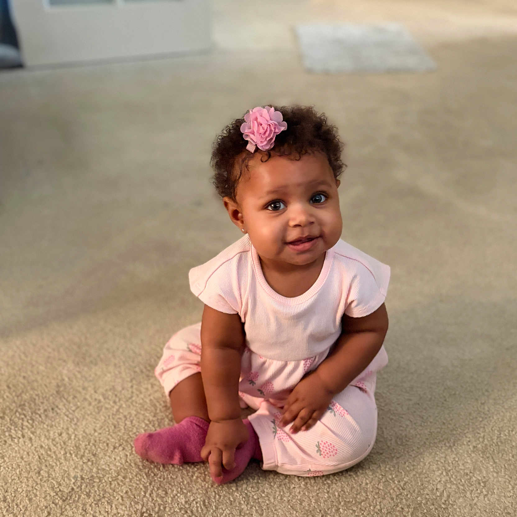 Xaya joined the competition — help win amazing prizes! baby, big_eyes, carpet, child, chubby_cheeks, curly_hair, cute, earring, flower_hairclip, home_interior, indoor, pink_outfit, playful, portrait, sitting, skin_tone, smiling, sock, soft_lighting, toddler
