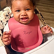 Xaya joined the competition — help win amazing prizes! baby, high_chair, bib, food, happy, smile, curly_hair, blue_eyes, kitchen, infant, child, feeding, star_pattern, clothing, person, cute, indoors, table, hands, face